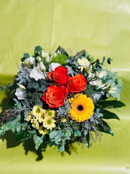 Blumenstrauß mit orangefarbenen Rosen, gelber Gerbera, weißen Knospen und grünem Beiwerk vor hellgrünem Hintergrund